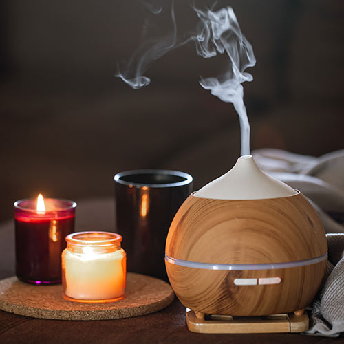 Enhance your living space with the help of Aromatherapy.  A photograph of an oil diffuser and candles