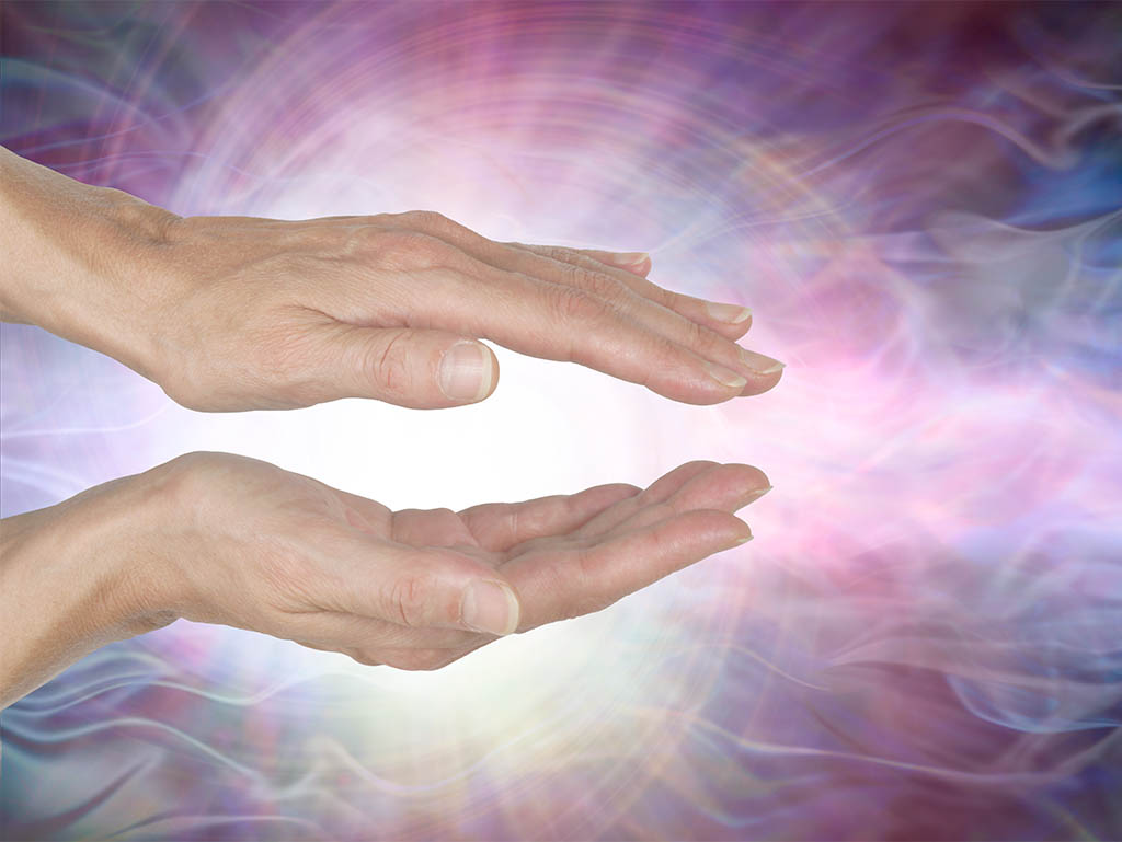 Reiki Distance Healing: Two hands showing an visual of reiki energy in the background